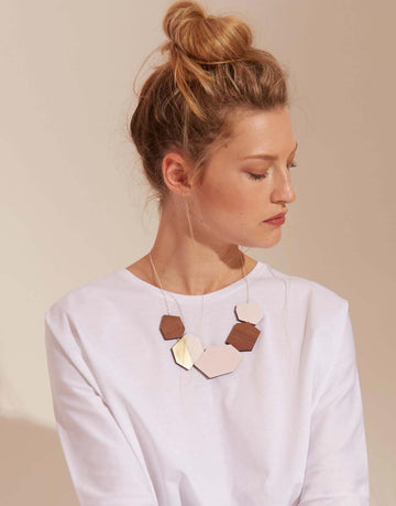 wooden statement necklace in pink and brass on model